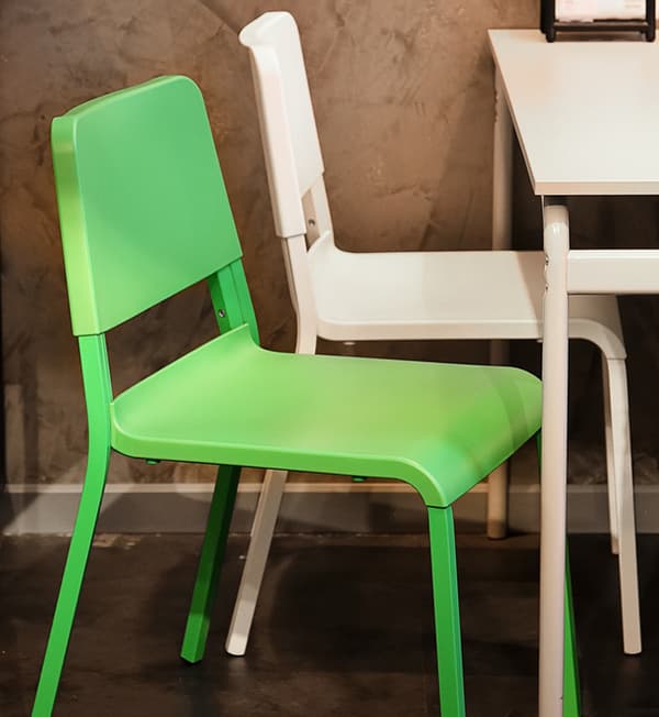 A green and white chair placed behind a white table.