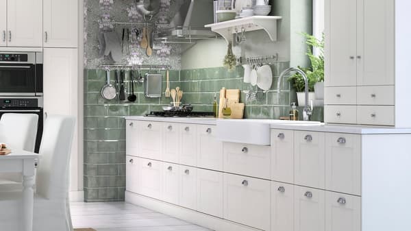 A green and white kitchen with 17 white kitchen drawers with chrome-plated cup handles and a white wall cabinet.