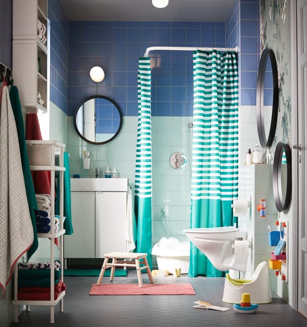 A green/blue bathroom with colourful and white interior and lots of rearrangeable storage for grown-ups and small children.