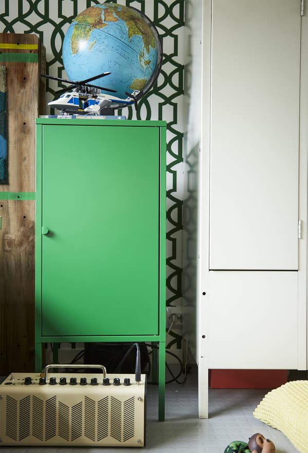 A green cabinet and patterned wall.