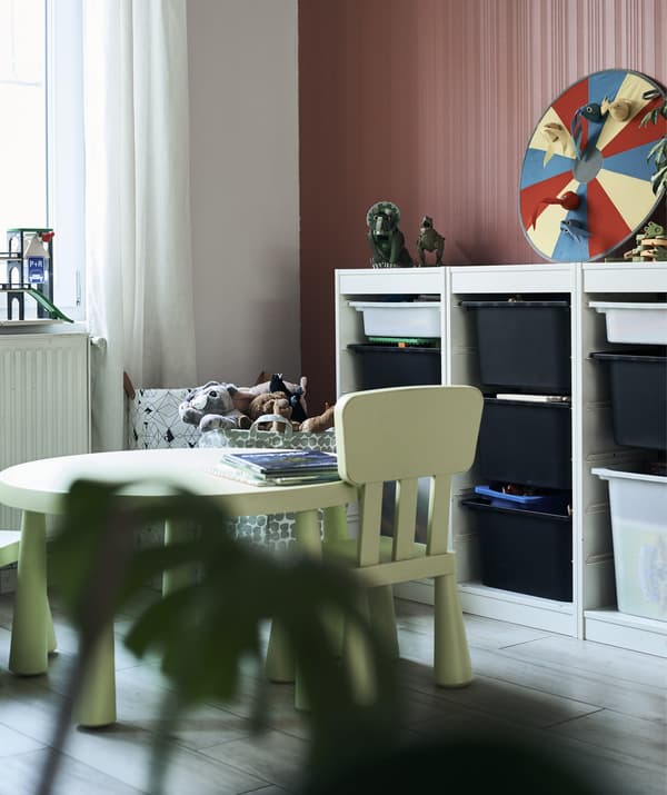 A green child’s table and chairs set and a storage unit with drawers.