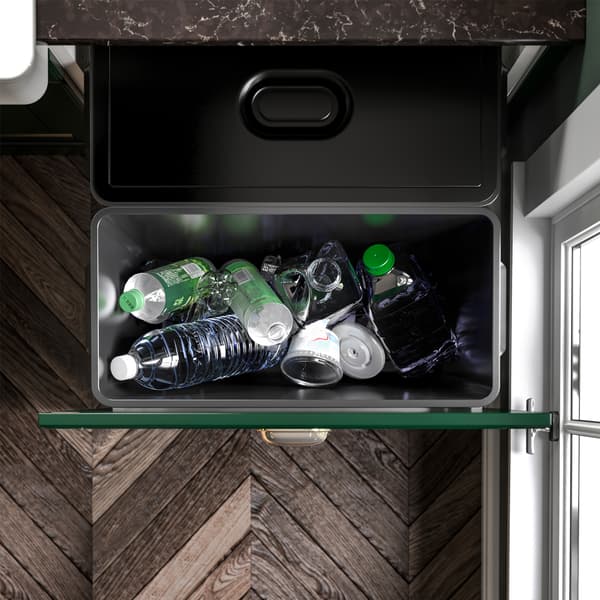 A green kitchen with an open drawer where VARIERA waste sorting bins in black are pulled out to show how to recycle.