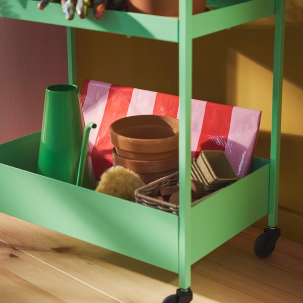 A green NISSAFORS trolley holding gardening tools, pots, and supplies neatly organised for easy access.