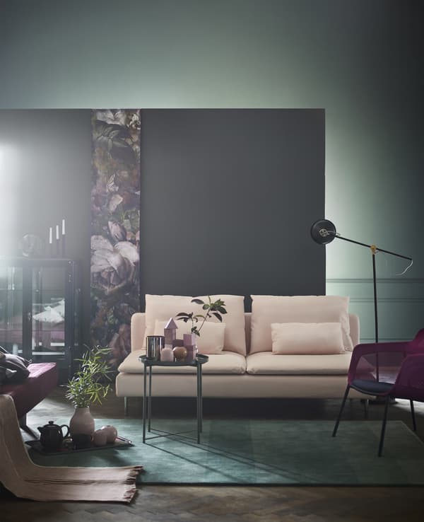 A green rug, green tray table, and light pink SÖDERHAMN three-seat section sofa in a living room with a grey wall.