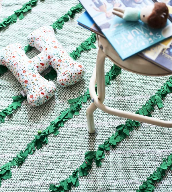 A green rug with cream stool and toys on top.