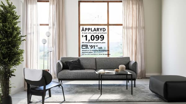 A grey APPLARYD grey sofa in a living room. Text above the sofa tells people they can use an installment plan to pay for the full price of the sofa of $1,099 at $91.58 per month for 12 months.