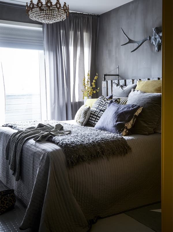 A grey bedroom with yellow flowers and cushions.