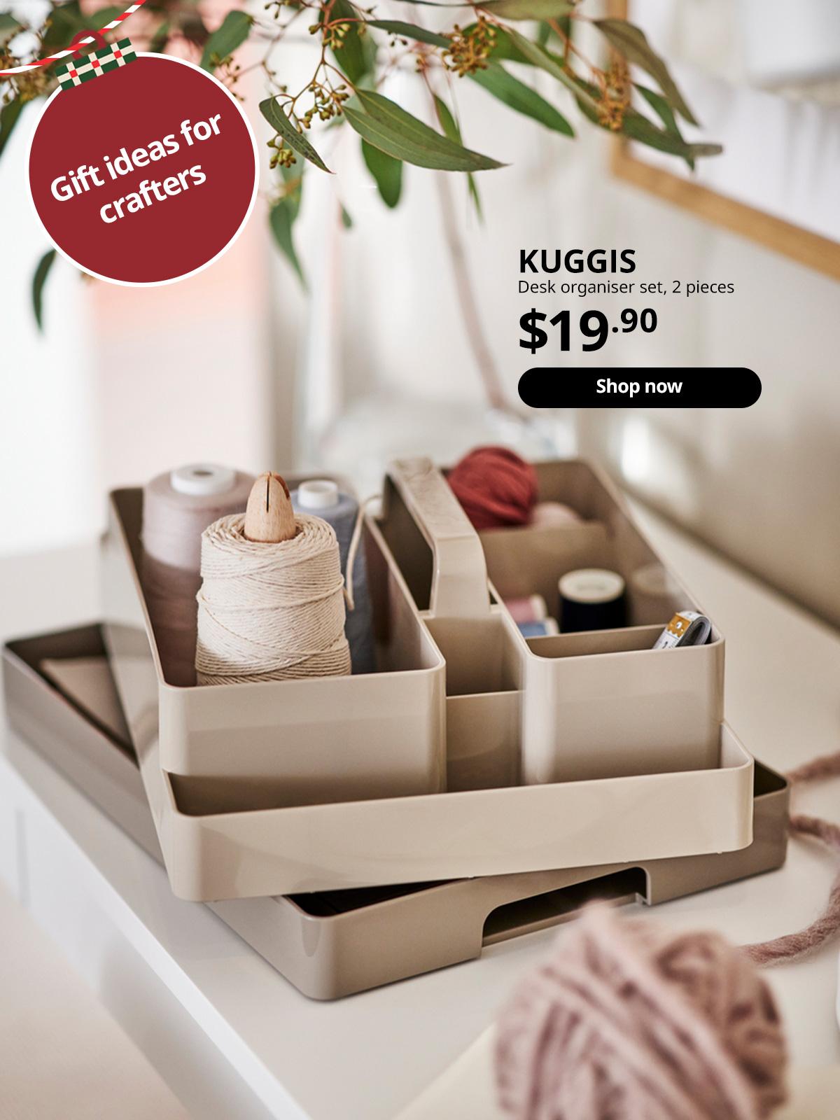 A grey-beige KUGGIS desk organiser set on a white surface holding different coloured sewing threads, with a plant overhead.