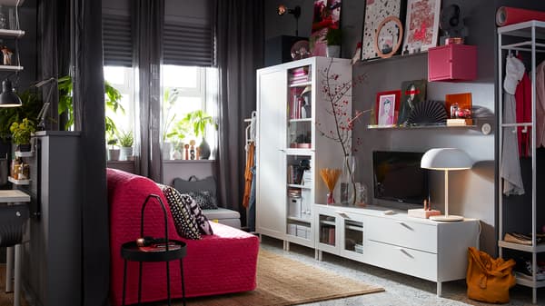 A grey living space with an IKEA PLATSA white media storage combination and a pink sofa.