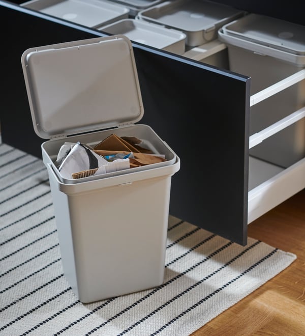 A grey recycling bin with papers inside.