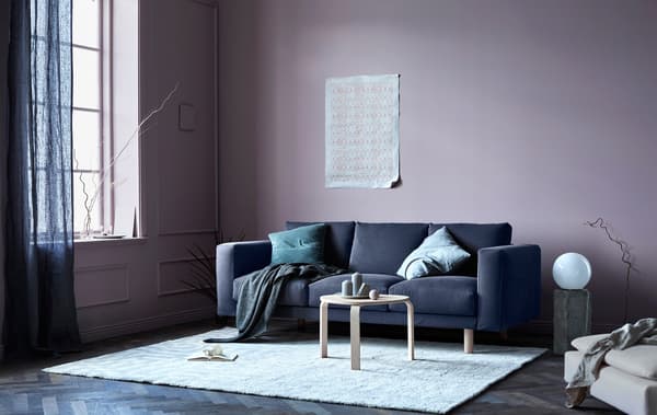 A grey sofa with cushions and throws in a living room with natural accents.