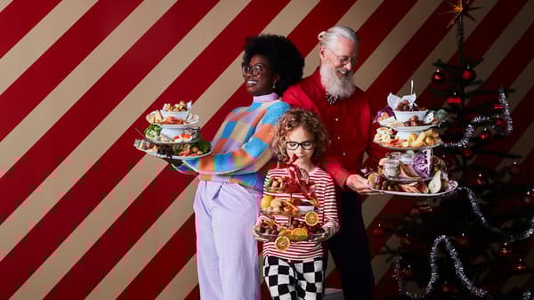 A group of 3 people holding tiered platters with food on them.