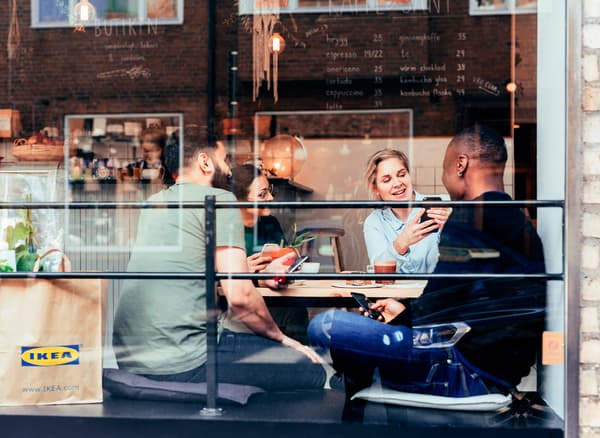 A group of friends having coffee in a coffeeshop with an IKEA paper bag beside them.