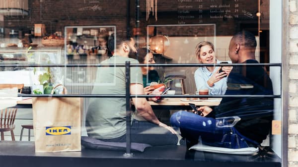 A group of friends having coffee in a coffeeshop with an IKEA paper bag beside them.