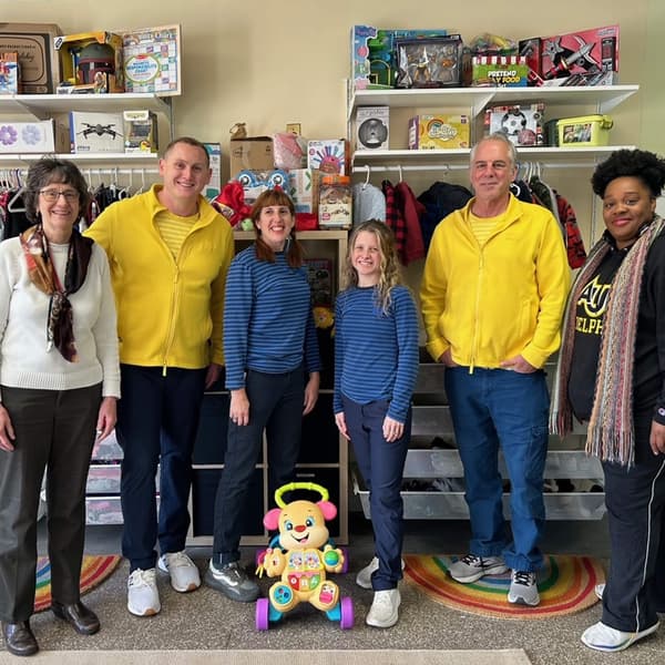 A group of IKEA co-workers in uniform smiling at a camera with the Family Promise team.
