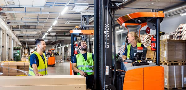 A group of IKEA coworkers standing together laughing at the distribution center.