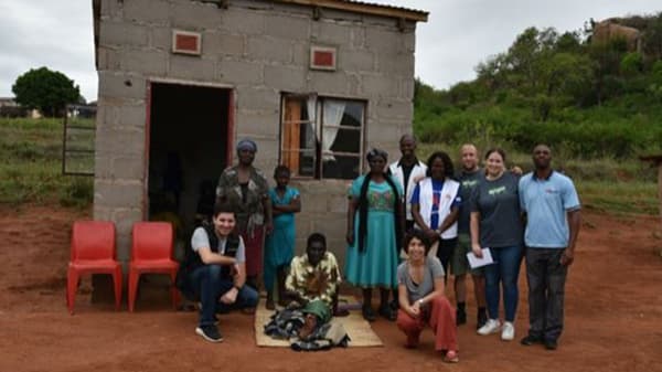 A group of people gathered outside a small home in Eswatini.