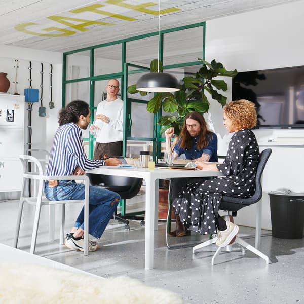 A group of people in an office space working around a shared table 