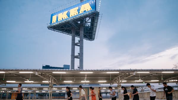 A group of people walking in front of a large sign.