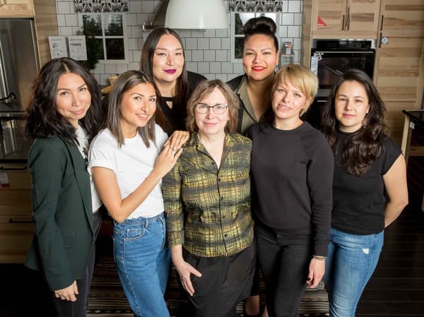 A group of Setsuné Indigenous Fashion Incubator designers standing together in an IKEA kitchen.