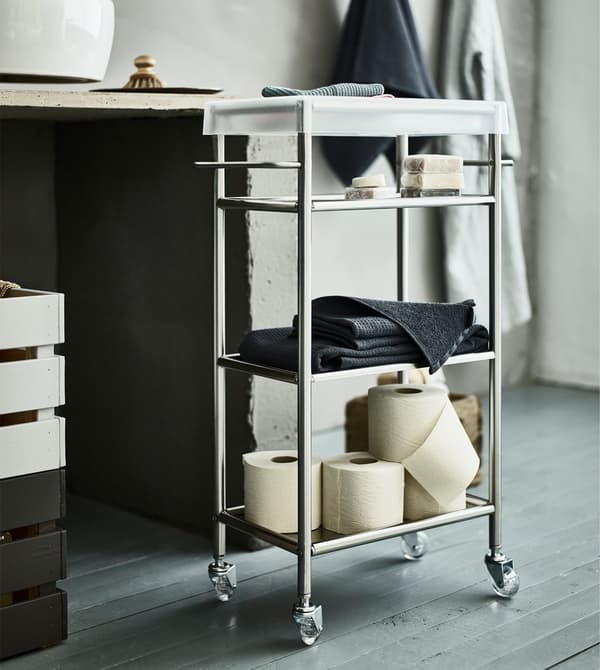 A GRUNDTAL trolley in a shared bathroom holding toilet paper and towels, etc.