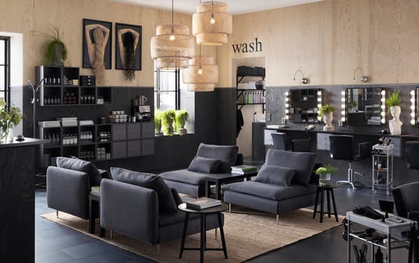 A hair salon furnished with low SÖDERHAMN dark grey armchairs and wall cabinets displaying shampoos.