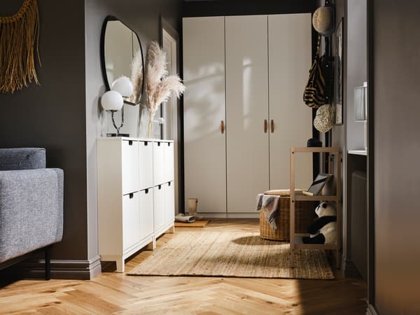 A hallway with a PAX/FORSAND wardrobe at one end and two white shoe cabinets with 4 compartments on one side.