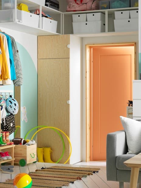 A hallway with a PLATSA wardrobe on one side of a door, with open shelving units and a MULIG clothes bar on the walls.