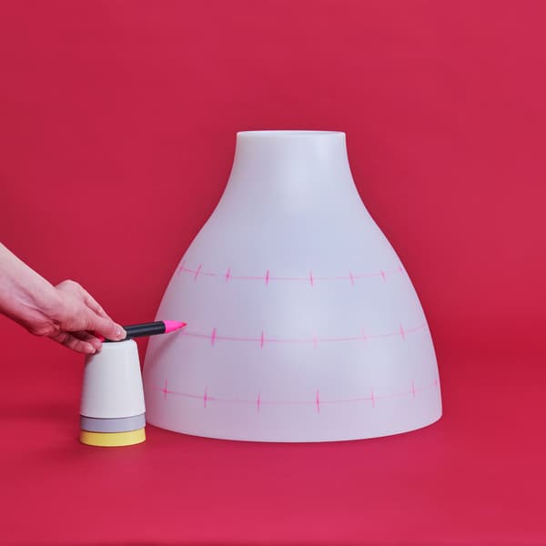 A hand is marking the points where wholes should be drilled into the lamp.
