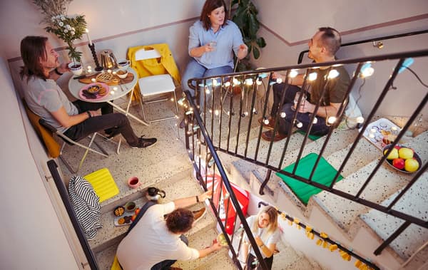 A handful of men and women, talking and sharing snacks while seated and spread over different levels of a stairwell.