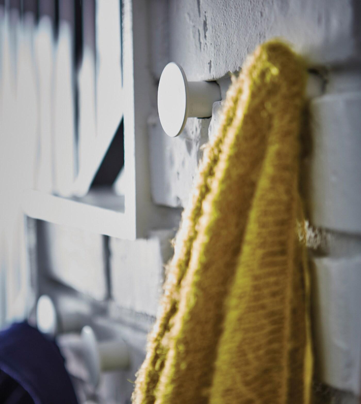A hanger on the wall with a yellow jacket.
