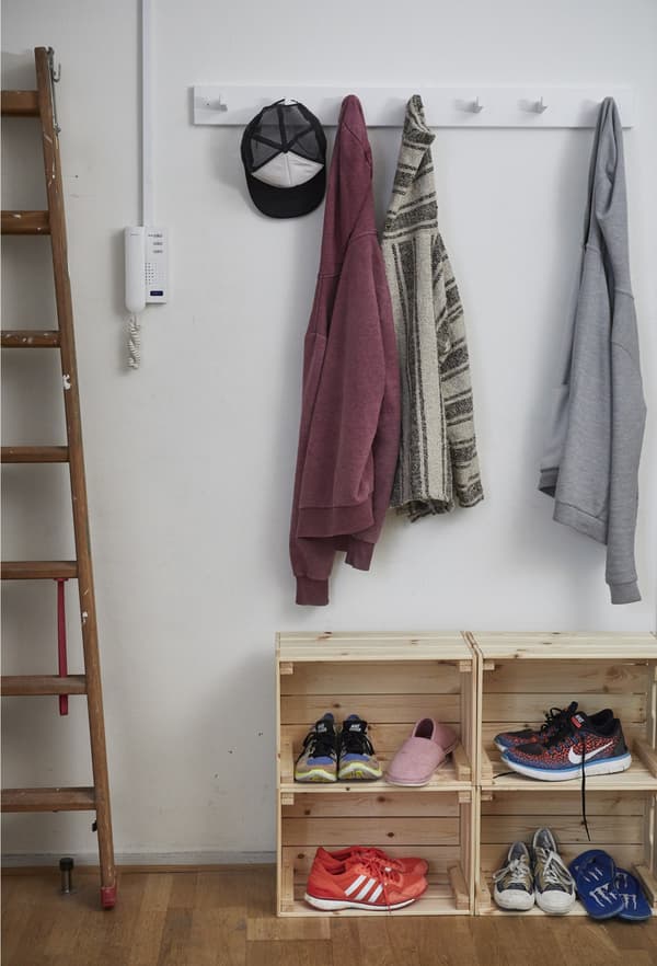 A hanging rack for coats and wooden crates for shoes in the hall of a communal apartment.