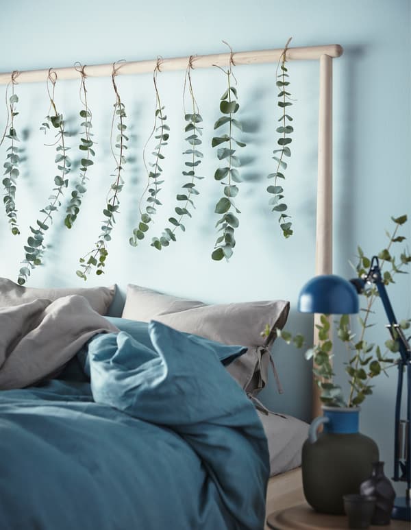 A headboard decorated with hanging greenery in a blue and brown bedroom.