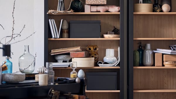 A HEMNES cabinet filled with ceramics, books, storage boxes and other objects.