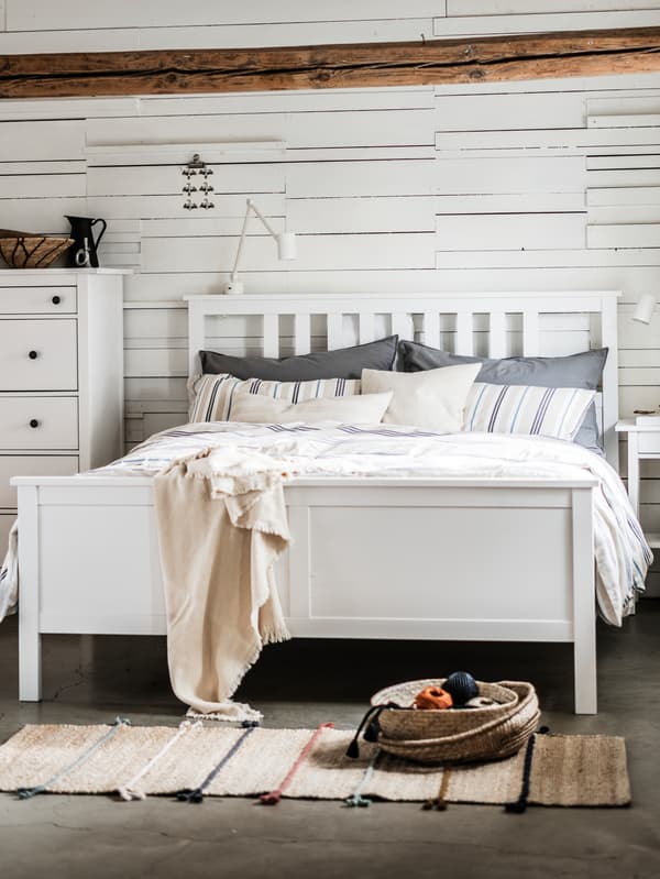 A HEMNES double bed stands in a bedroom against a wall next to a HEMNES chest of 6 drawers.
