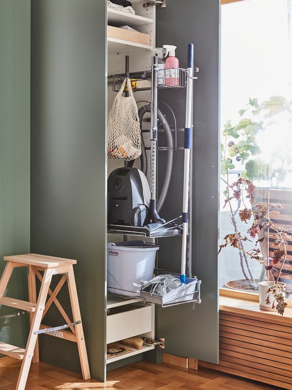 A high cabinet with an open grey-green BODARP door has a cleaning interior fitting inside holding cleaning utensils.