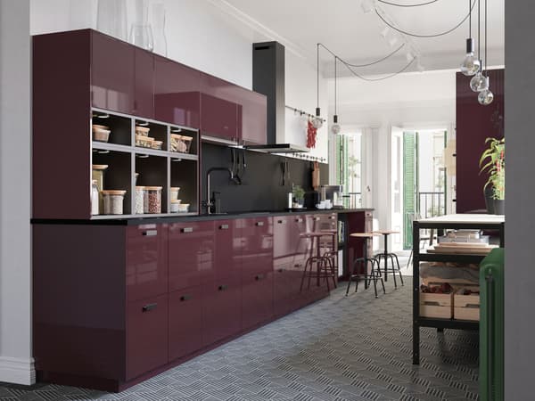 A high-gloss kitchen in dark red-brown, a hexagon-patterned floor and naked light bulbs on cords that hang from the ceiling.