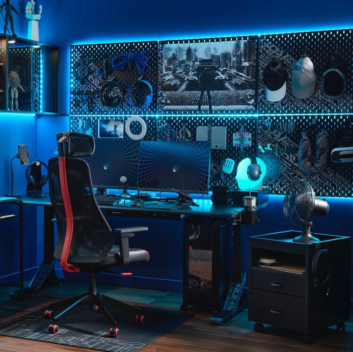 A high-tech gaming room with blue LED lighting and two monitors on a desk with a black MATCHSPEL gaming chair in front.