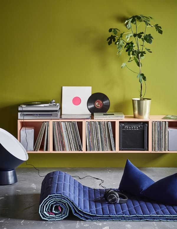 A home DJ-station with record storage made of IKEA EKET cabinets mounted on a green wall.