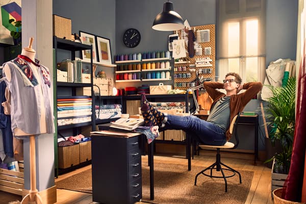 A home office for a tailoring business; a guy sitting back on a chair with his feet on the desk.