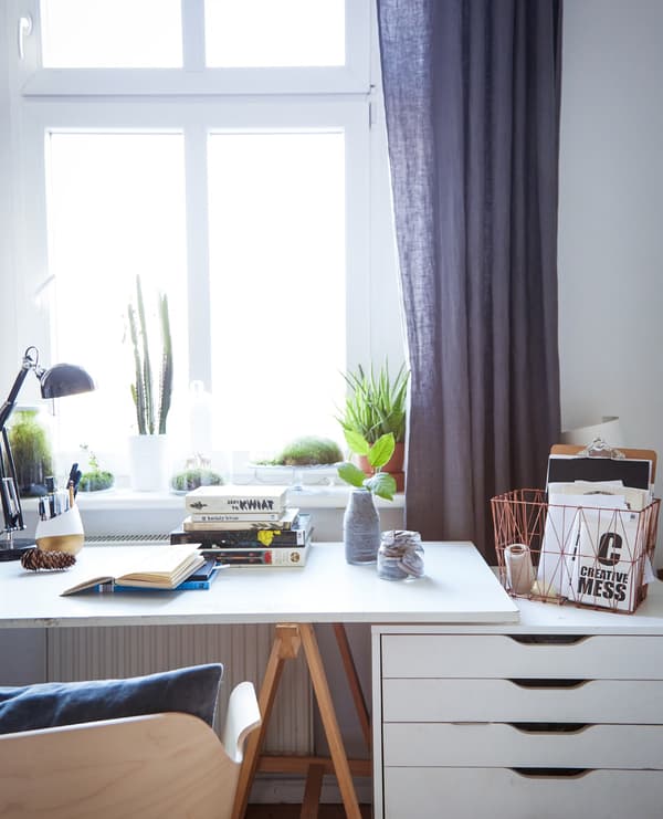 A home office work station, including desk and cabinet, placed in front of a large window.