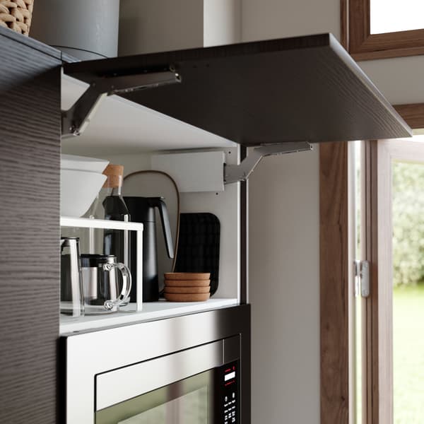 A horizontal kitchen door in dark brown ash effect is open. A black thermos, bowls and a glass carafe are stored inside.