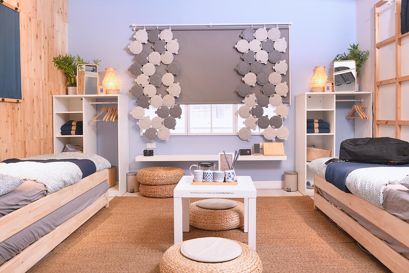 A hostel area featuring two single-sized beds, a cabinet and a wooden frame hung that is holding a towel.