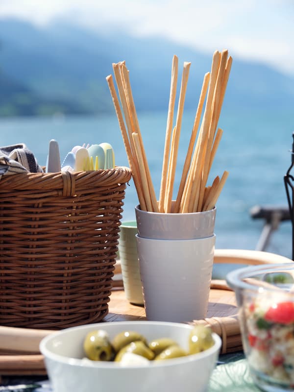 A KALAS mug filled with bread sticks and a small bowl filled with olives