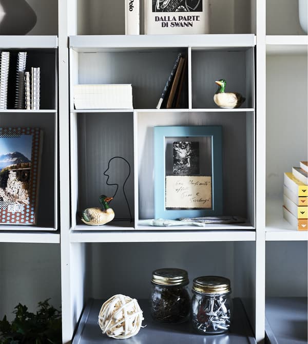 A KALLAX unit with divider inserts and display objects.