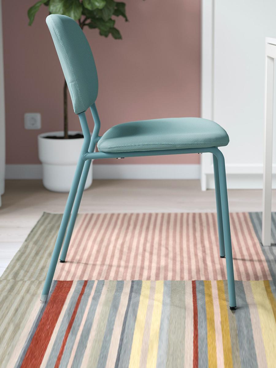 A KARLJAN turquoise-coloured chair is placed on a rug in a dining area at home.