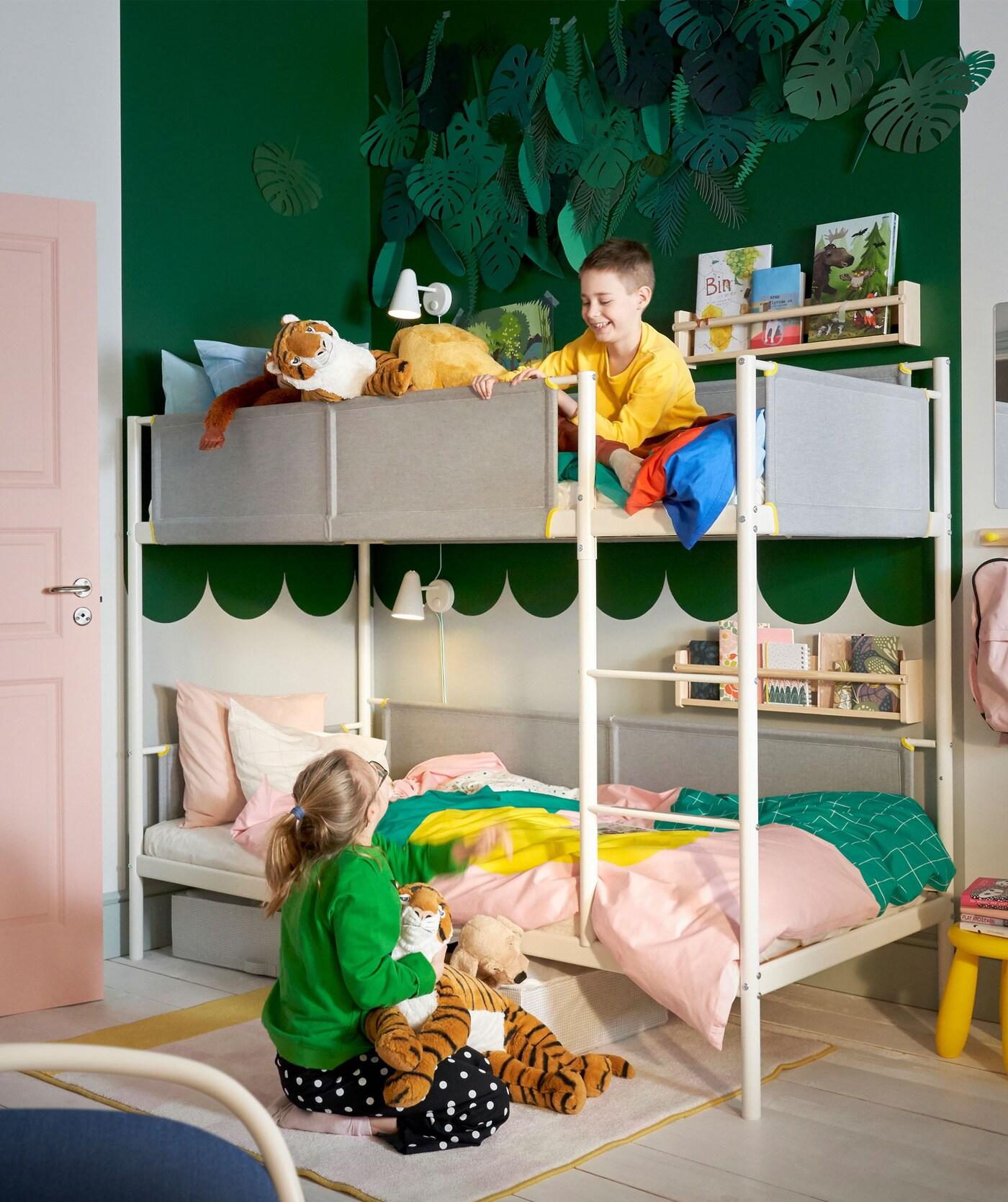A kid seating infront of a bunker bed with toys