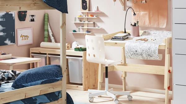 A kid’s room decorated/painted in pale pink with light wooden furniture including a desk and bunk bed.