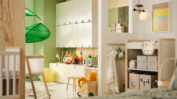 A kids room partially separated by a wall. One side has SMÅSTAD cabinets and toys. The other has a baby changing area.