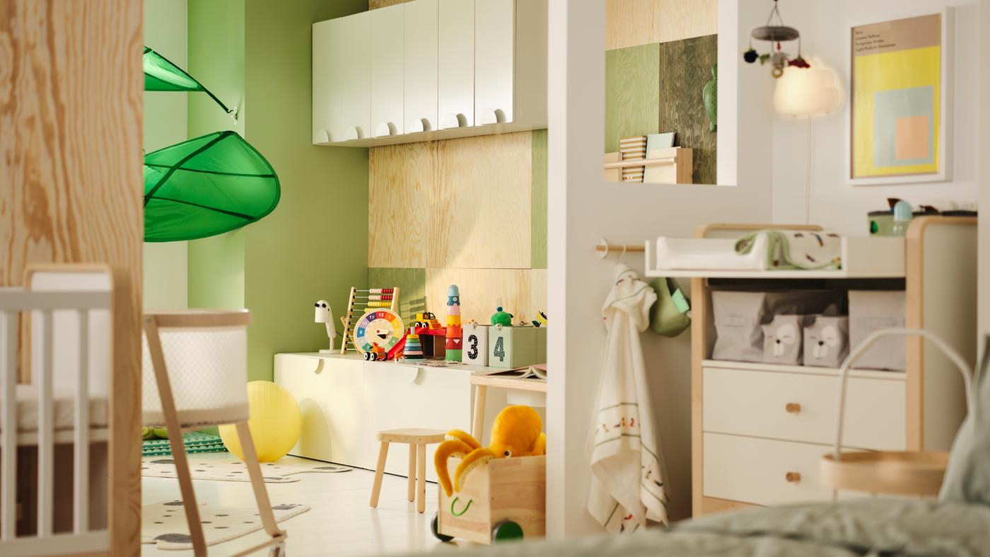 A kids room partially seperated with a wall. One side has SMÅSTAD cupboards and toys. The other has a baby changing area.